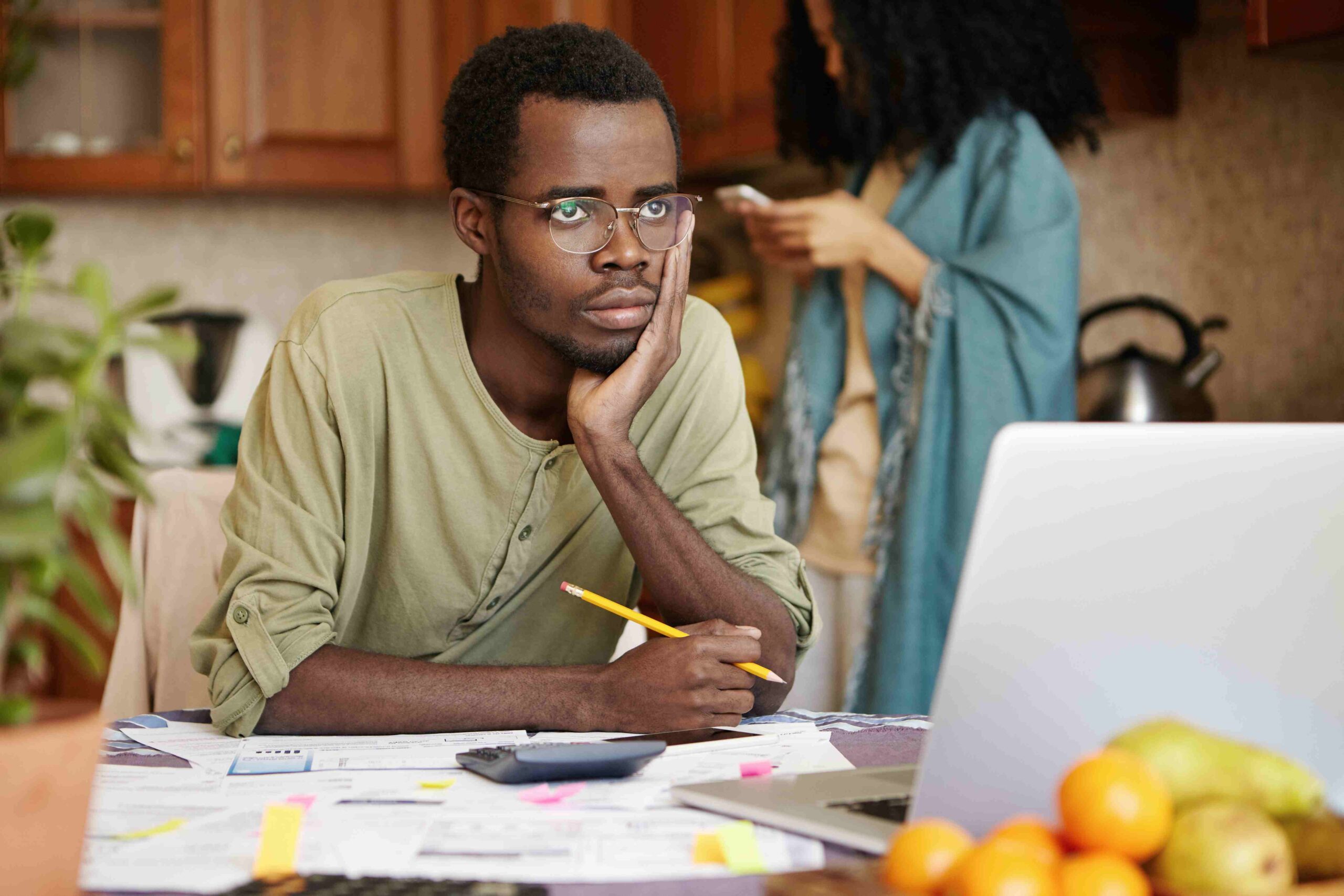 A young Nigerian man with glasses looking stressed and confused at his laptop, representing the frustration of trying to find the best freelancing skills to learn.
